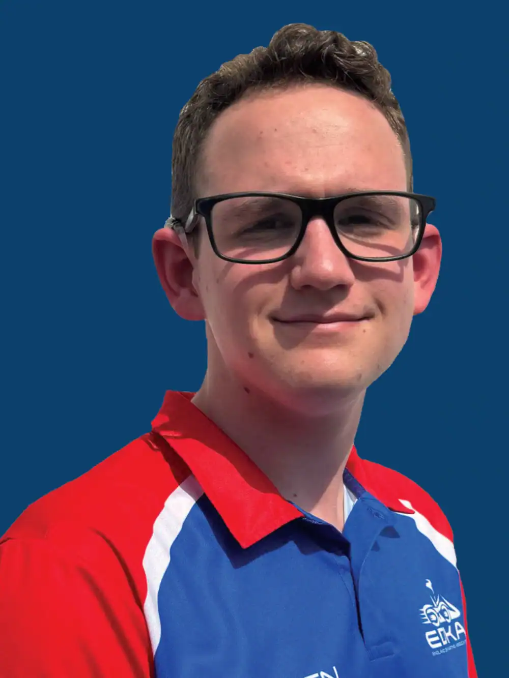 A person wearing glasses and a blue and red collared sports shirt stands in front of a solid blue background.