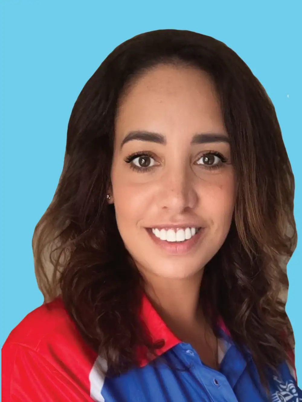 A woman with shoulder-length brown hair and a red, blue, and white collared shirt smiles in front of a solid light blue background.